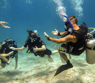 An instructor leads a group of new divers on a sandy bottom.